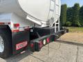 A rear view of a 2010 Freightliner M2 106 truck showing the black bumper with red and yellow lights and a white tank mounted on the back