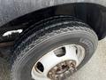 Close-up of a tire from a 2011 Dodge Ram 5500 showing its rugged tread and wheel rim with visible bolts and some water droplets on the tire surface