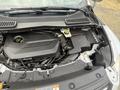 The engine compartment of a 2014 Ford Escape showing the engine cover and various components including hoses and connectors