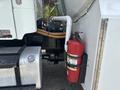A 2010 Freightliner M2 106 truck with a visible engine compartment and a red fire extinguisher mounted on the side