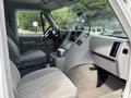 Interior view of a 1994 GMC Vandura 3500 showing the driver's seat dashboard and control panel with gray upholstery and a central console
