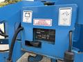 A blue Genie TZ-34/20 aerial lift with labels detailing electrical specifications and battery charger information