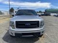 A silver 2014 Ford F-150 facing forward with a black grille and distinctive headlights