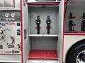 A metal cabinet with open doors showing two vertical mounts with red straps designed to secure equipment inside a fire truck