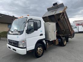 A 2008 Mitsubishi Fuso FE180 truck with a raised dump bed and a side-mounted storage compartment