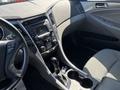 Interior view of a 2015 Hyundai Sonata featuring a dashboard with a center console radio display gear shifter and seats in gray fabric
