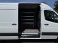 A 2019 Mercedes-Benz Sprinter van with the side door open, revealing an empty interior with shelving and a flat floor