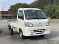 A white 2010 Daihatsu Hijet truck with a compact design featuring a flatbed and a single cab with two doors