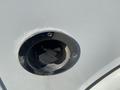 A close-up view of a silver fuel filler door for a 2011 Chevrolet Express featuring a circular black opening and screw fasteners around the edges