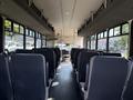 Interior of a 2021 Ford Econoline van featuring rows of dark seats arranged along the sides and a central aisle leading to the front dashboard