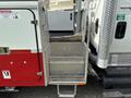 A 2012 International 7300 Workstar with a silver diamond plate step and a red cabinet on the side featuring safety labels and warning signs