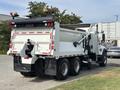 A 2013 International WorkStar truck with a white body and red and black markings equipped with a dump bed and rear mounted spreader