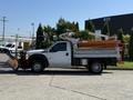 A white 2011 Ford F-550 truck equipped with a snow plow attachment and a truck bed with orange sides and a utility body