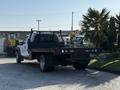 A white 2014 Ford F-550 flatbed truck with a black stake body and rear lights visible, parked with a focus on its cargo area