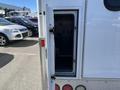 A 2013 Chevrolet Express with an open side door revealing an empty storage compartment