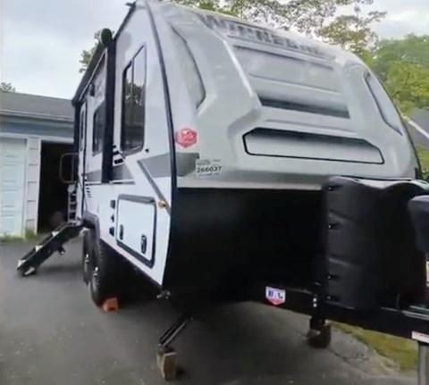 A 2020 Winnebago MICRO MINI travel trailer with a sleek design featuring a white exterior and a compact layout, positioned on a set of stabilizing legs