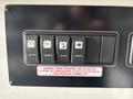 A control panel with multiple switches and a warning label related to the operation of a 120-volt AC system in a vehicle