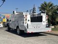 A white 2011 Ford F-550 service truck with a flatbed and toolboxes on the sides visible light bar and safety lights on the rear