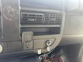 A close-up view of the dashboard of a 2018 Chevrolet Express featuring air vents a power outlet and a circular dial