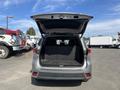 A silver 2018 Toyota Highlander with its rear hatch open revealing a spacious cargo area with a textured rubber mat