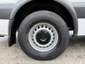 A close-up view of the wheel of a 2012 Mercedes-Benz Sprinter showcasing a silver alloy rim and a large black tire