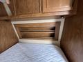 Interior view of a 2013 Outdoor Wind River showcasing wooden cabinetry and a bed with a white mattress