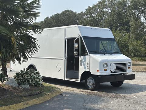 A white 2018 Ford Econoline van with an open side door parked on a road