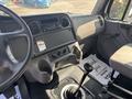 Interior view of a 2014 Freightliner M2 106 truck showcasing the dashboard gear shifter and seating area with controls and an audio system