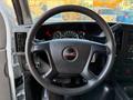 A 2015 GMC Savana steering wheel with a black finish and the GMC logo in the center featuring dashboard gauges and controls in the background