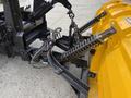 A close-up view of the front attachment of a 2016 International 7600 featuring heavy-duty spring components and a yellow snow plow blade