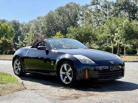 A black 2006 Nissan Fairlady convertible parked with its top down showcasing sleek lines and chrome wheels