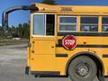 A yellow 2006 Thomas Saf-T-Liner HDX school bus with a red stop sign attached to the side and a large front mirror