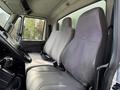 Interior view of a 2014 International TerraStar truck featuring two cloth-covered front seats in gray with a central console and seatbelts visible