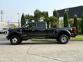 A black 2021 Ford F-350 SD pickup truck is shown from the side view with a crew cab and large wheels parked on a concrete surface