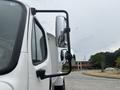 A 2006 Freightliner M2 106 truck with a prominent side mirror extending from the driver's side near a clear reflection