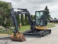 A 2017 John Deere 50G excavator with a black and yellow exterior positioned with its boom raised and a bucket attached at the front