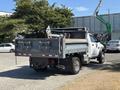 A 2016 RAM 5500 flatbed truck with a gray body and wooden bed in the rear showing equipment and tools secured in the truck bed