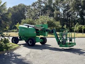 A green 2015 JLG 450AJ cherry picker with an extended platform and large tires positioned on a road