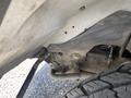 Close-up view of a 2023 GMC Savana's undercarriage showing a metal bracket and part of the suspension system with visible dirt and wear on the components
