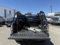 A 2010 Toyota Tacoma truck with an open bed displaying aluminum ladders and a variety of equipment inside