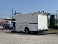 A 2011 Workhorse W62 delivery truck with a white exterior and blue stripe parked with its rear doors partially open