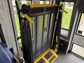 A wheelchair lift with a black mesh barrier and yellow handles installed in a vehicle designed for accessibility