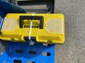 A bright yellow toolbox with a black handle and labeled "TOOL BOX" on the top, secured with a white strap