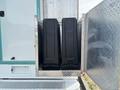 A silver storage compartment holding two black containers on a 2020 Freightliner MT45 vehicle