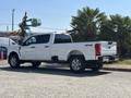 A 2023 Ford F-350 Super Duty pickup truck in white with a crew cab and a 4x4 badge parked on a driveway