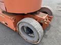 A close-up of a 2009 JLG E300AJP lift with large rubber wheels showing some wear and an orange chassis featuring directional arrow stickers