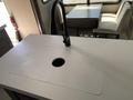 A close-up view of a kitchen countertop with a circular sink cutout and a sleek black faucet