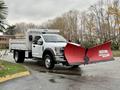 A white 2021 Ford F600 equipped with a red snow plow attached to the front and a bed for hauling materials in the back