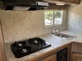 Interior view of a kitchen in a 2018 Westland Travelaire featuring a black gas stove with four burners and a stainless steel sink