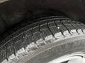 A close-up view of a black tire with a tread pattern showing dirt and water droplets on the surface of a Subaru Forester